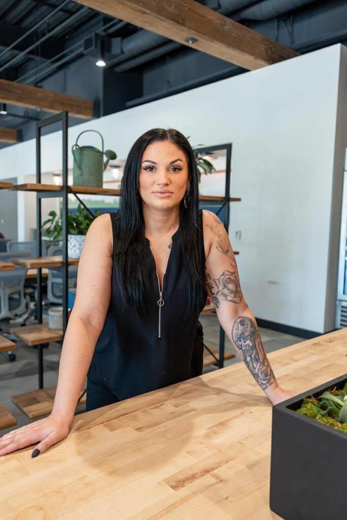 Common Desk McKinney Brand Photo of a woman with black hair, dressed in black with arm tattooes