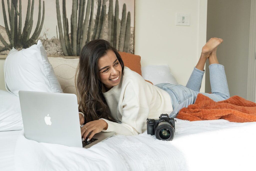 how to choose a photography niche, woman laying on bed at laptop, how to book more brand photography clients