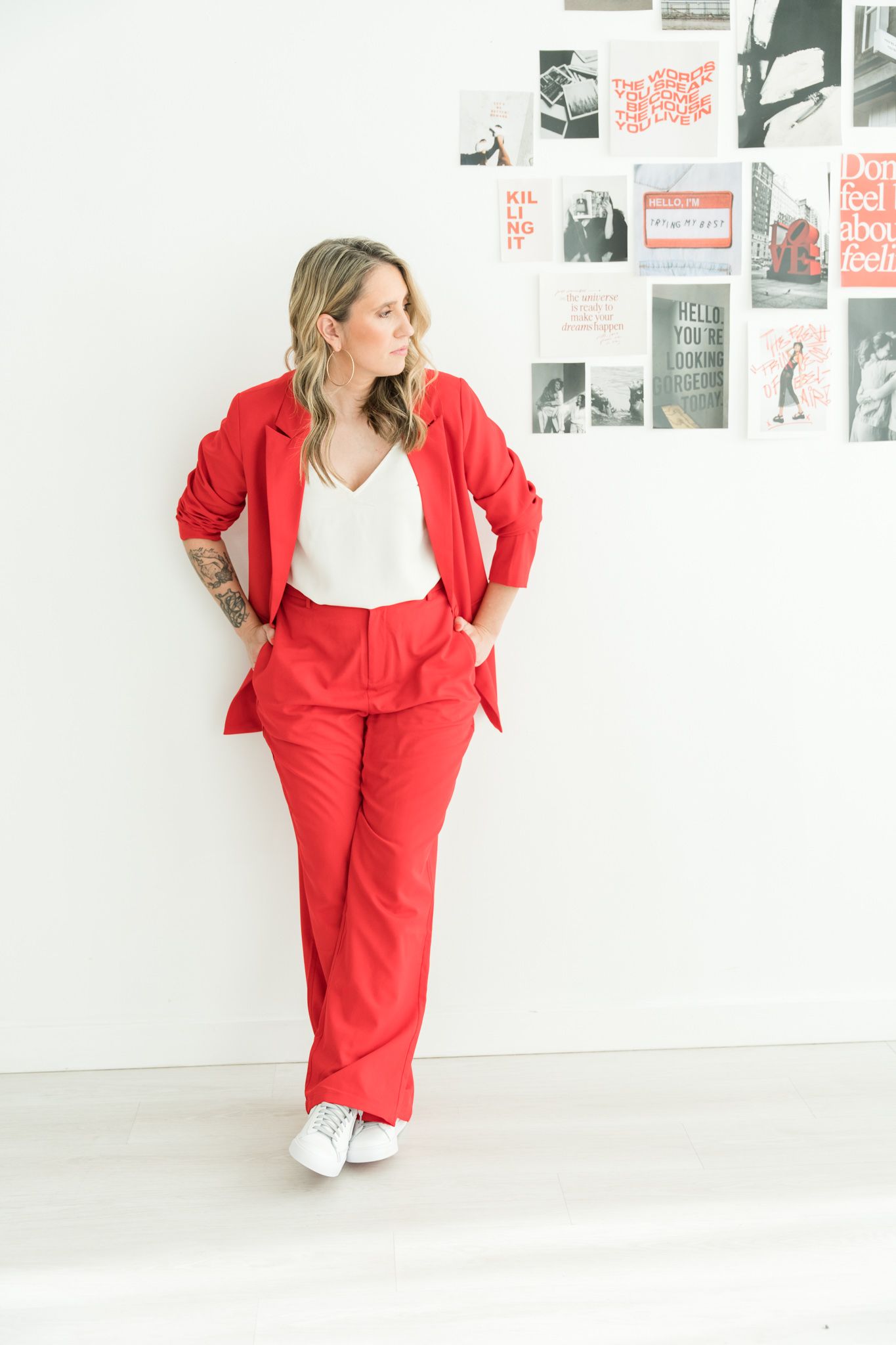 woman in red suit with sneakers standing against a wall - what to wear for brand photoshoot